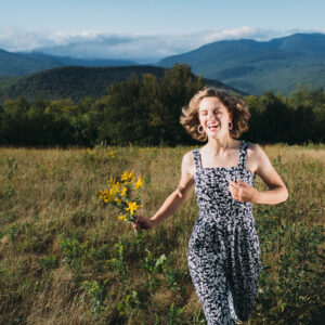 Young woman's mountain meadow, senior portrait session in Jackson, NH. Senior photos in the White Mountains by Birch Blaze Studios. © 2021 Birch Blaze Studios.