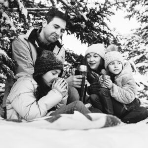 Family drinking hot chocolate under snowy pine trees. NH winter family lifestyle photography session by Birch Blaze Studios. https://birchblaze.com
