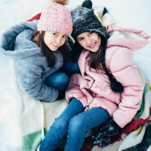 Two girls snuggling in a Hudson Bay blanket. New England winter family lifestyle photography session by Birch Blaze Studios. https://birchblaze.com
